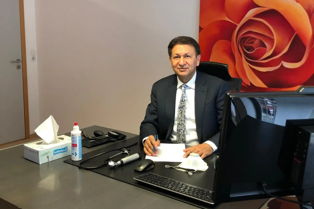 Dr. med. univ. Dost Mohammad at his desk in the consulting room