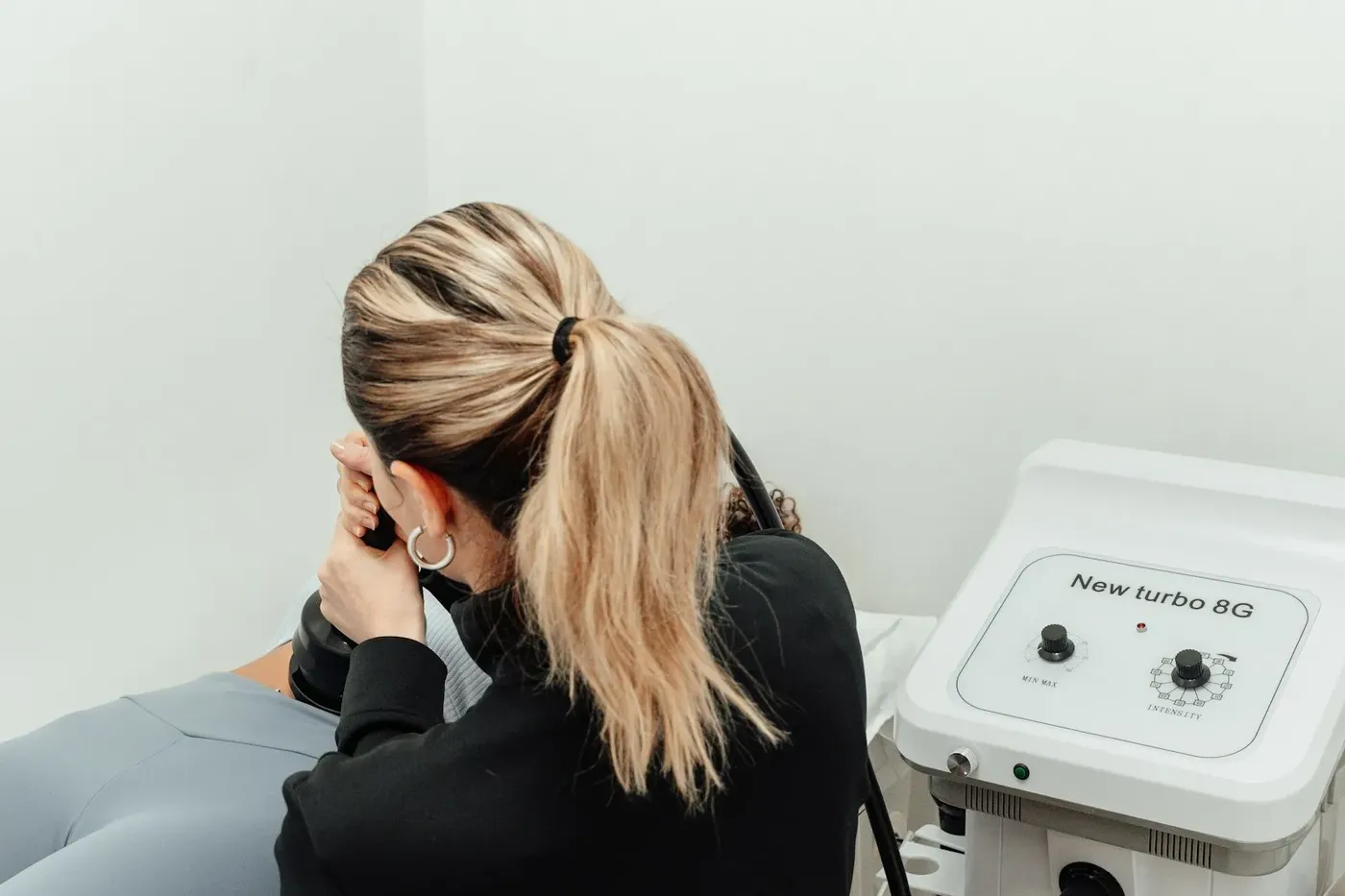 A patient sitting in a plain treatment room beside a device