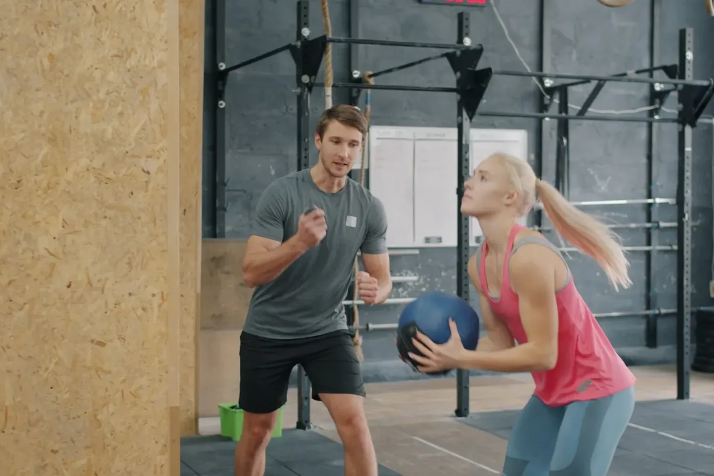 Trainer und Athletin beim Training mit einem Medizinball
